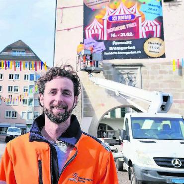 Kampf mit Sugus und Konfetti - Sein Team räumt auf: Oliver Burgunders Mitarbeiter nehmen das grosse Fasnachtsplakat wieder vom Spittelturm. Bild: Marco Huwyler