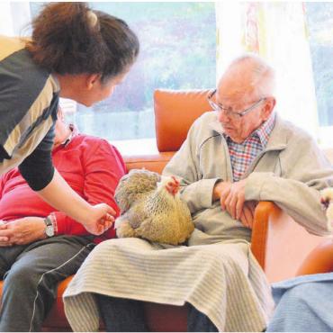 Mehr als Eier- und Fleischlieferant - Tierpflegerin Cornelia Trinkl bringt Mensch und Tier zusammen. Auch der weisse Hahn Napoleon geniesst die Streicheleinheiten. Bild: Sabrina Salm