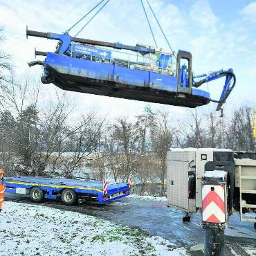 Schlammsauger für die Fische - Riesensauger im Anflug: Der Saugbagger wird per Lastkran vom Schwertransporter in das Wasser gehoben. Von hier aus saugt er rund einen Monat lang das verschlammte Wasser aus der Stillen Reuss zum Entwässerungsplatz, wo dieses gereinigt wird. Bilder: Marco Huwyler / zg