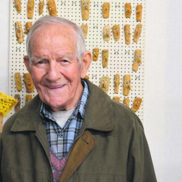 Holz zum Leben erwecken - Der Künstler mit zwei grossen und ganz vielen kleinen Figuren: August Gauch umgeben von einer kleinen Auswahl seiner vielen Schnitzereien. Bild: Annemarie Keusch