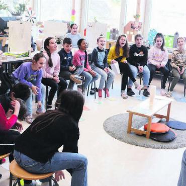 Für einmal eine Klasse spielen - Wie reagiert eine Klasse, wenn die Lehrerin ein Diktat ankündigt? Unter Anleitung von Autor Paul Steinmann (rechts) üben die Kinder die Szene mehrfach. Bild: Chregi Hansen