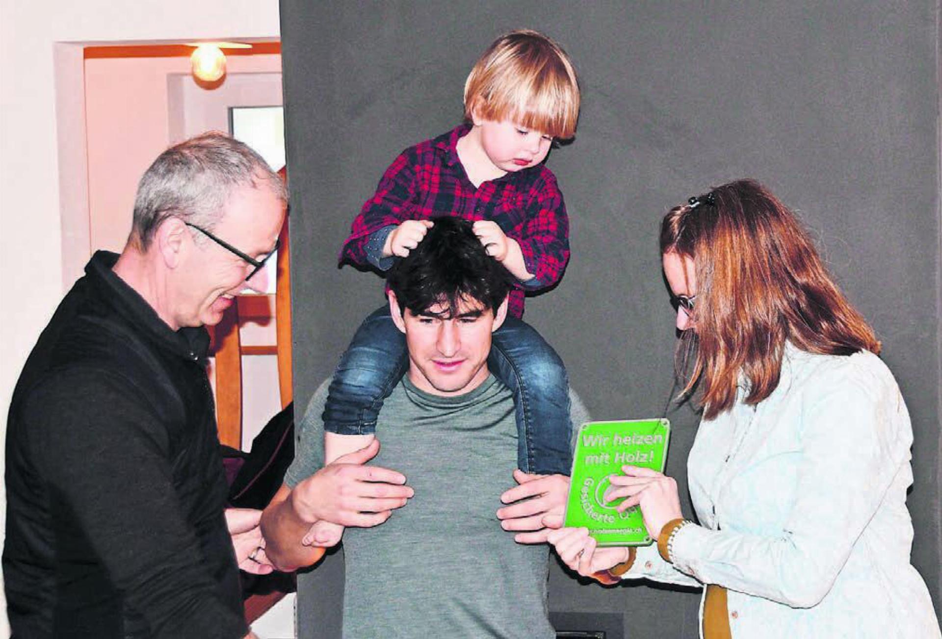 Übergabe des Holzenergiepreises vor der modernen und klugen Hafnertec-Feuerung (v. l.): Stefan Staubli, Präsident von Holzenergie Freiamt, übergibt die Auszeichnung an die Familie Jasmin und Fabio Caduff mit Sohnemann Curdin. Bild: Daniel Marti