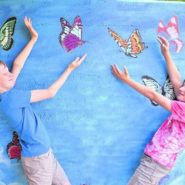 Am Reussufer in Ozean tauchen - Interaktive Kunst: Zwei beteiligte Schüler präsentieren ihr Werk. Neben den hier zu sehenden Schmetterlingen wurde die Mauer mit vielerlei weiteren Motiven aufgehübscht. Bilder: as