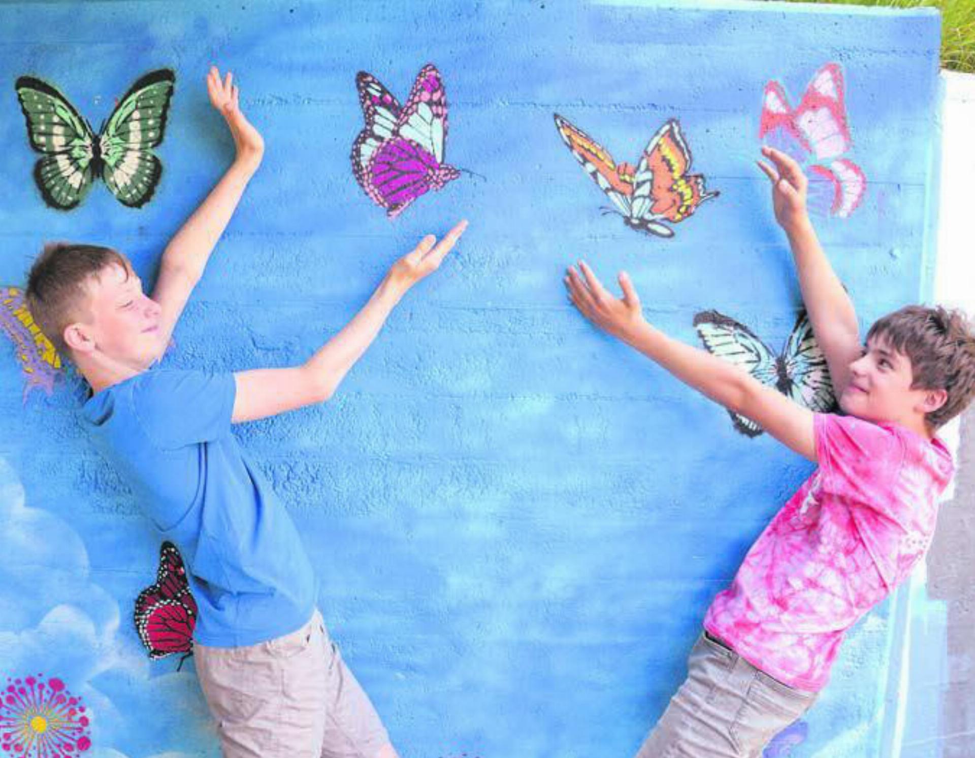Interaktive Kunst: Zwei beteiligte Schüler präsentieren ihr Werk. Neben den hier zu sehenden Schmetterlingen wurde die Mauer mit vielerlei weiteren Motiven aufgehübscht. Bilder: as