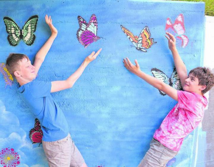 Interaktive Kunst: Zwei beteiligte Schüler präsentieren ihr Werk. Neben den hier zu sehenden Schmetterlingen wurde die Mauer mit vielerlei weiteren Motiven aufgehübscht. Bilder: as