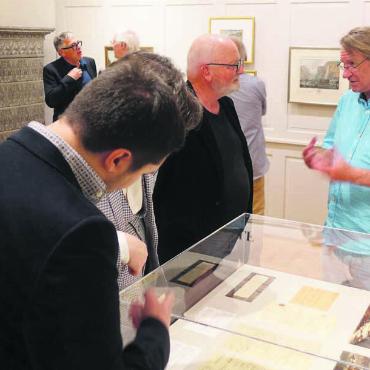 Klein, aber mit grosser Bedeutung - Kurator Peter Fischer (rechts) unterhält sich mit den Vernissagebesuchern über die neuen Exponate. Bild: Susanne Schild